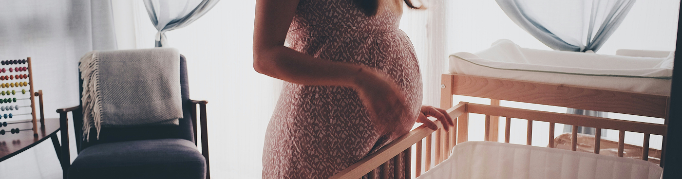 A pregnant woman standing in front of the crib